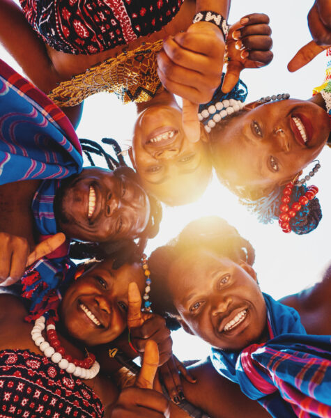 People with typical kenyan clothes hug and smile together