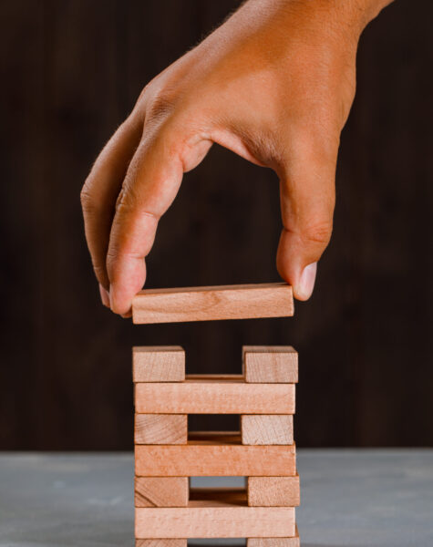 Business project concept on wooden and plaster background side view. man building up tower.